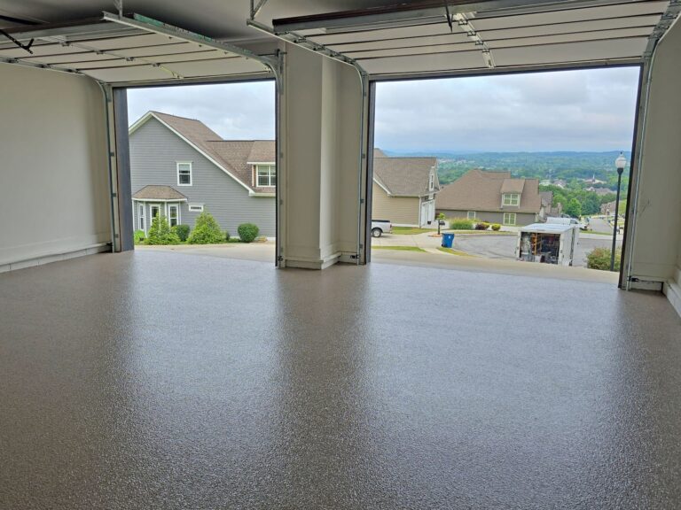 Three-car garage with seamless gray epoxy flake flooring overlooking a residential neighborhood