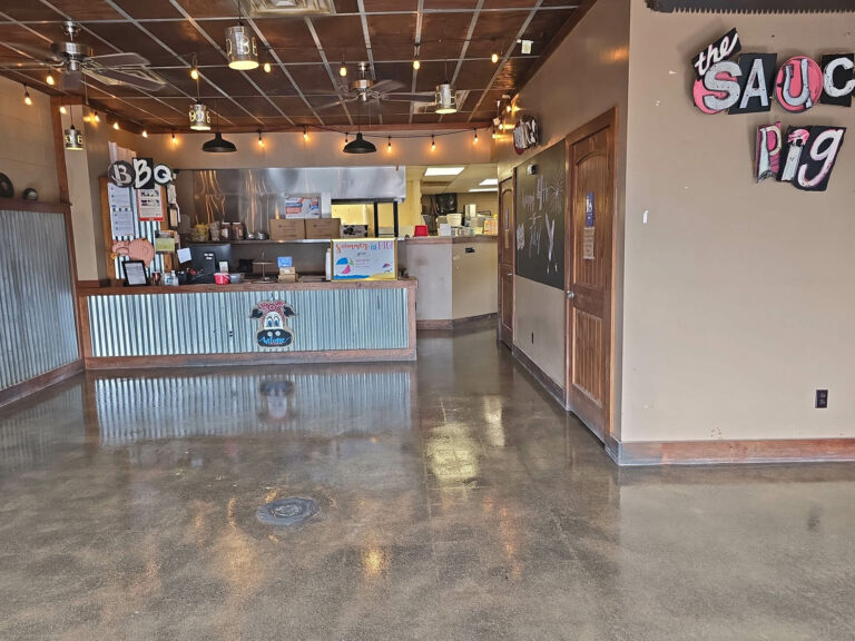 Polished concrete restaurant floor with glossy finish at a BBQ eatery featuring rustic wood and corrugated metal decor