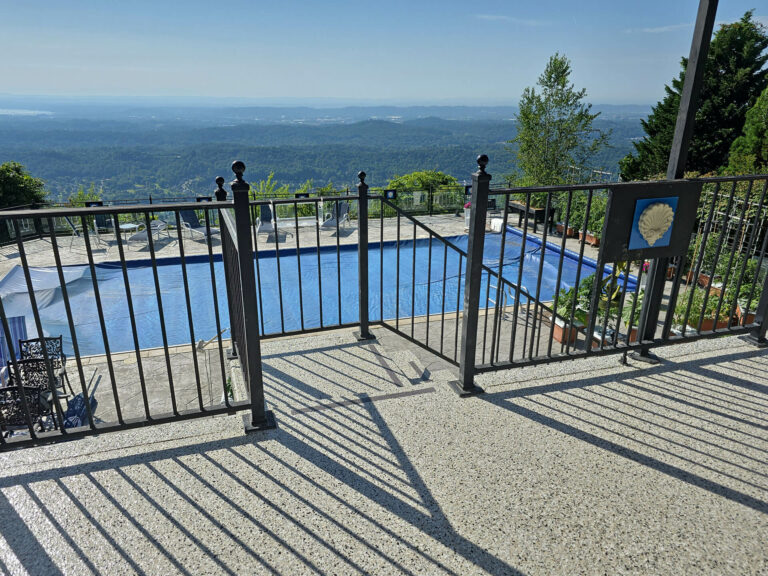 Outdoor patio and pool area with slip-resistant epoxy flake coating and metal railing overlooking scenic mountain views
