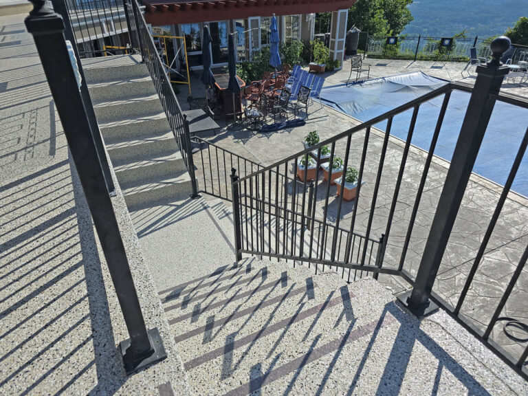 Outdoor staircase and patio area with slip-resistant epoxy flake coating leading to a pool deck overlooking scenic views