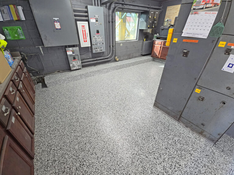Industrial epoxy flooring with gray and white flake blend in a utility room, designed for heavy-duty use and chemical resistance