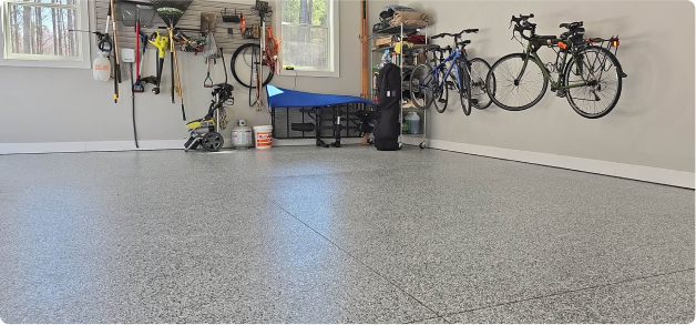 Epoxy flake garage floor with light gray finish in a modern residential garage featuring wall-mounted bikes, organized storage, and natural lighting