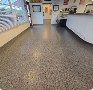 Seamless gray epoxy flake floor installed in commercial retail or restaurant space with counter area