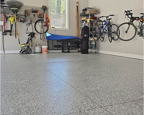 Epoxy flake garage floor with light gray finish in a modern residential garage featuring wall-mounted bikes, organized storage, and natural lighting